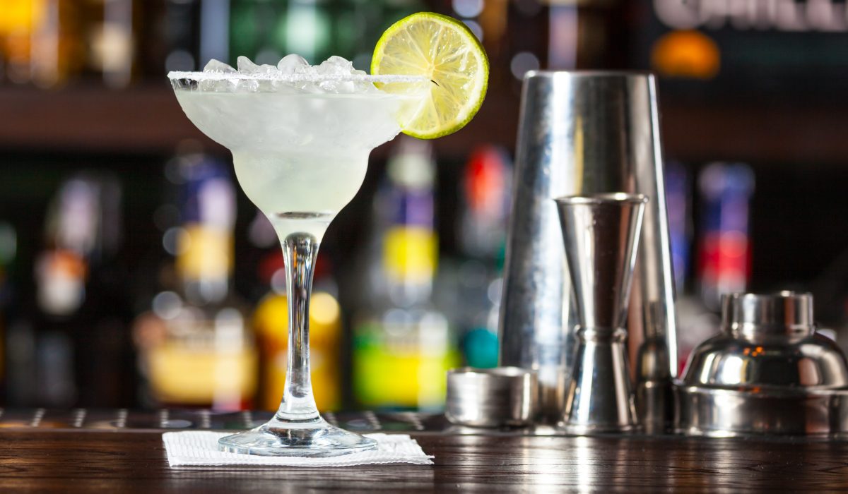 Cocktail garnished with lime standing on the bar counter.